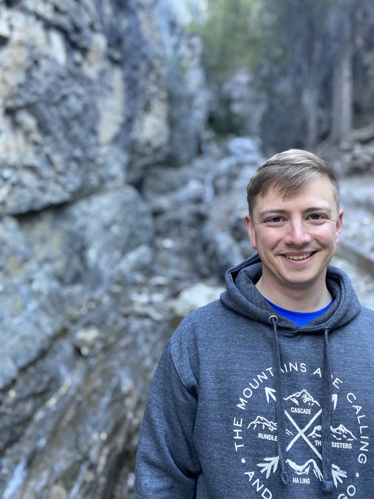 Scott smiling outdoors among rocky canyon walls