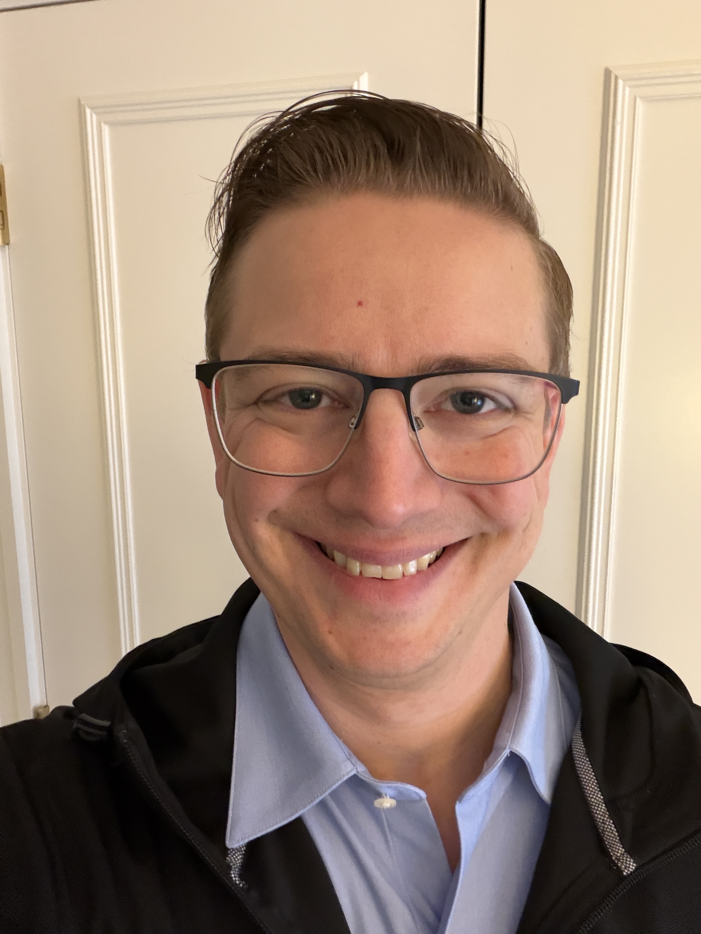 Scott smiling, wearing glasses and a blue collared shirt